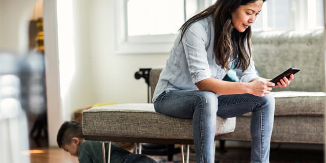 Woman sitting on couch using Virtual Home Inspection service to file insuracnce claim.