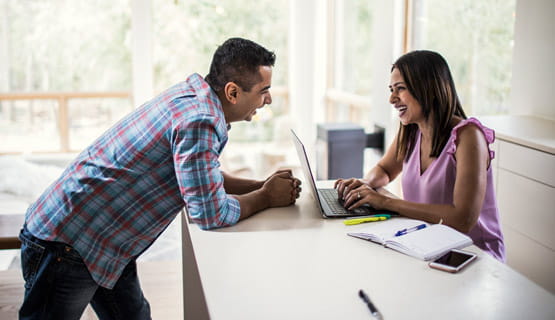 Couple using computer at kitchen counter