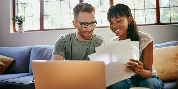 Young couple looking at paperwork and a laptop