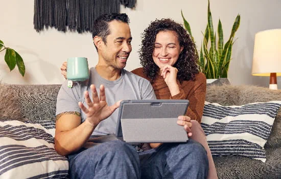 Couple sitting on couch working on a tablet.