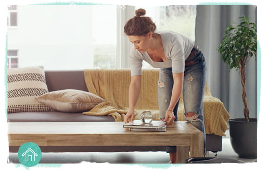 woman in a living room reducing clutter on the coffee table