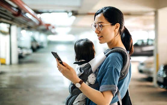 Woman carrying child and looking at smartphone