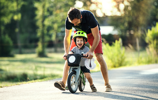 Dad helping child ride bike