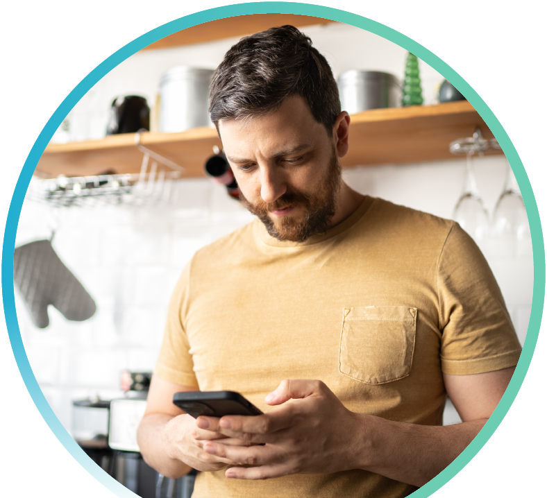 Man browsing their phone in their kitchen.