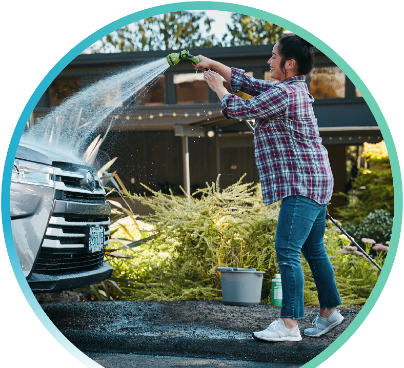Woman spraying down the hood of their car with a hose.