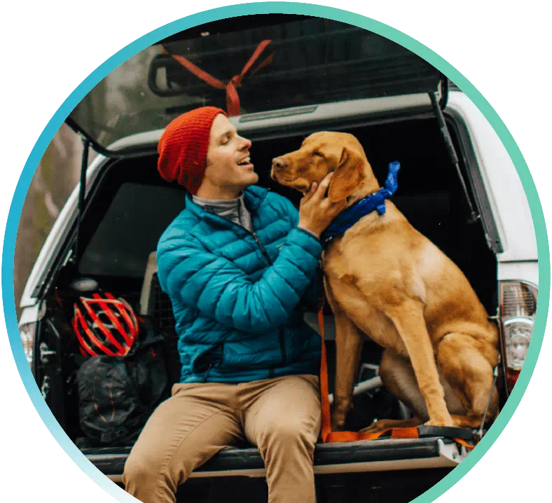 Guy showing affection to their dog in the back of their car.