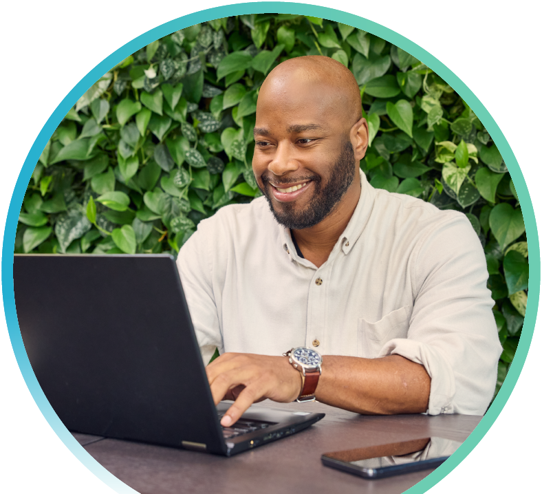 Man working on his laptop with green leaves in the background.