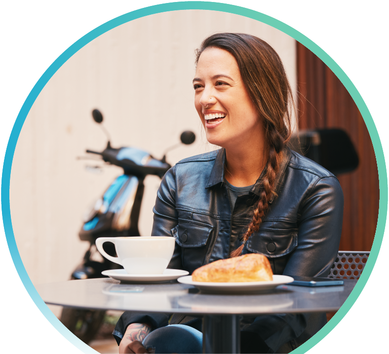 Woman enjoying coffee and a pastry at a restaurant. There is also a bank in the background.