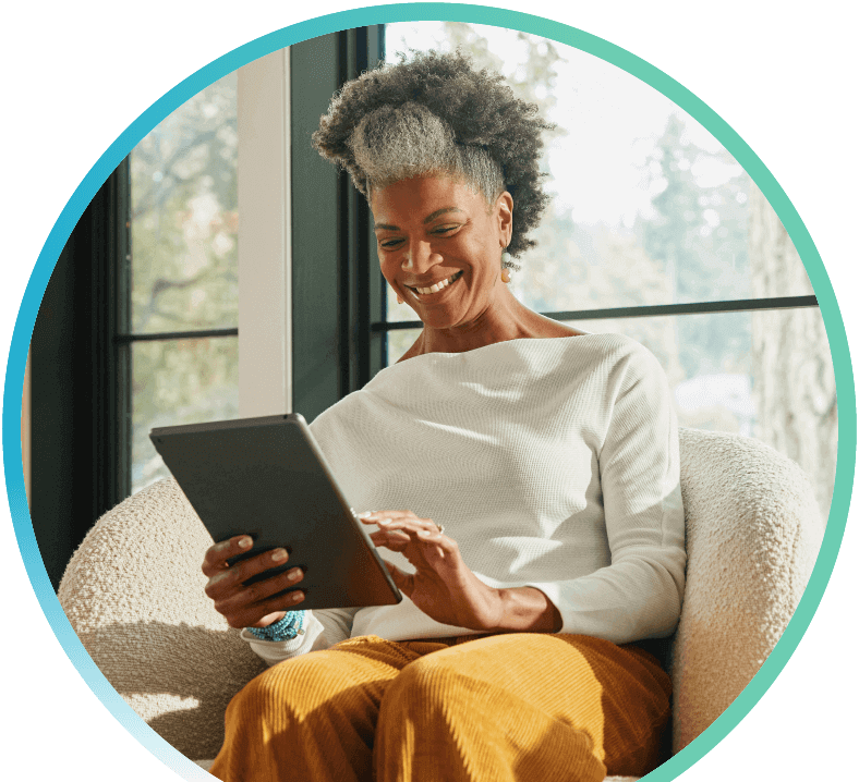 Woman sitting on a sofa inside while on a tablet.