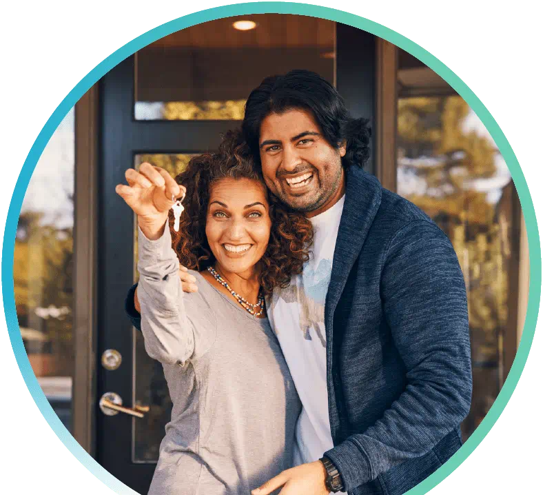 Husband and wife celebrating the purchase of a new home. The wife is dangling keys in front of the camera.