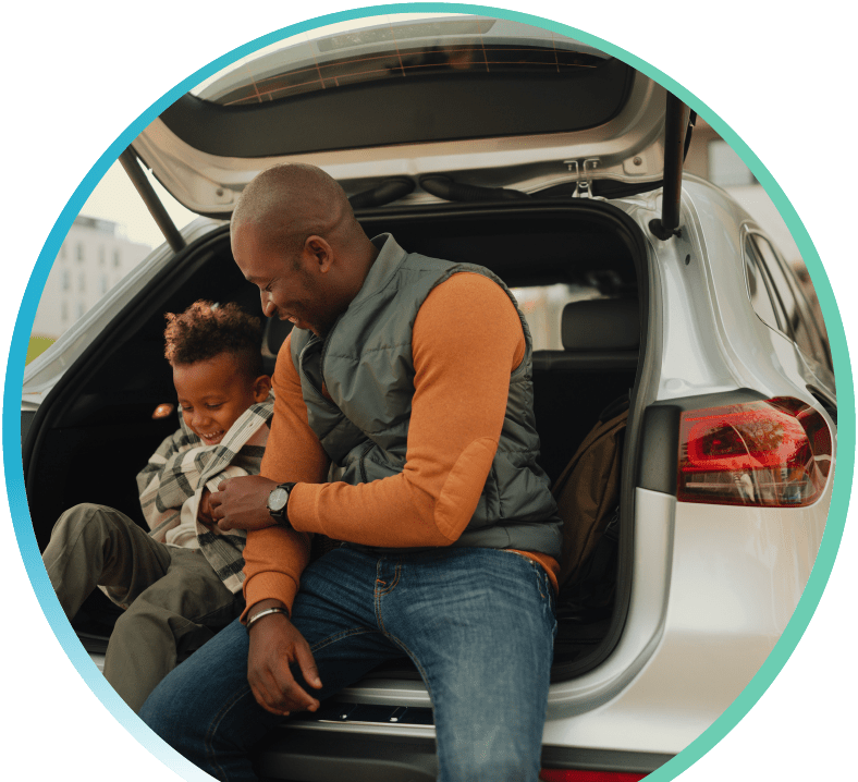 Man and child seated in the back of a car with a hatch back