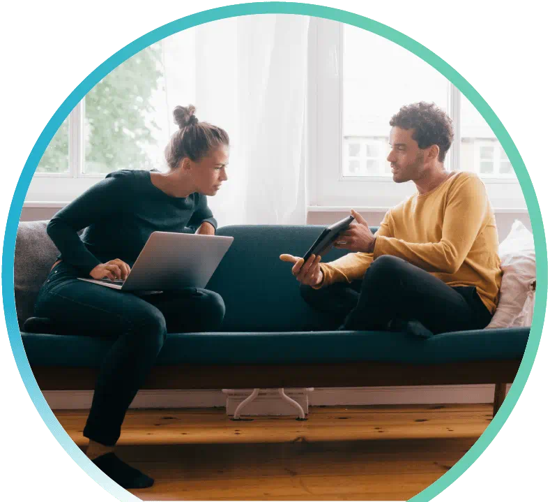 Woman with a laptop computer and man with a tablet sitting on a sofa