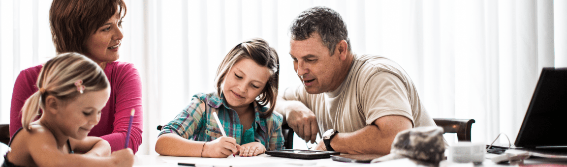 Parents gathered around there kids who are writing on and coloring paper.