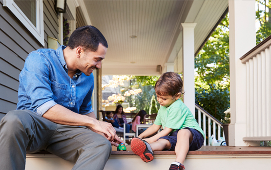 Father and son playing with toys on a front porch.